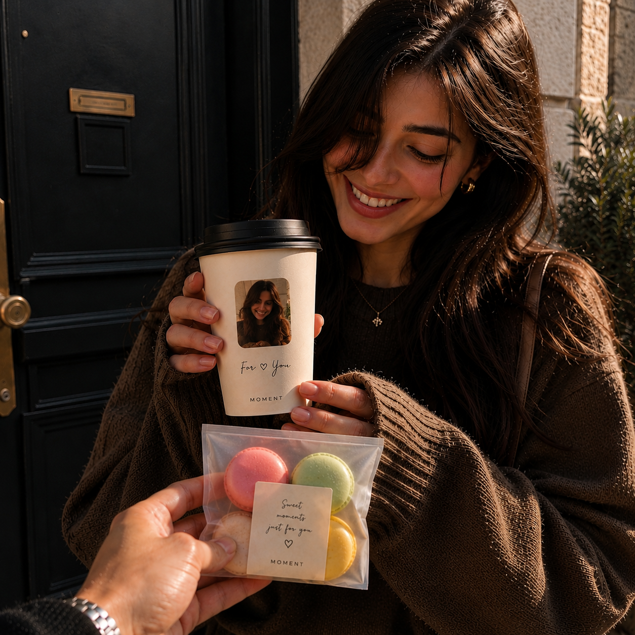 Smiling recipient holding MOMENT coffee and macarons.